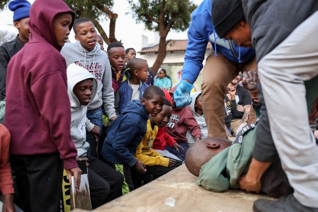 Young spectators watch as a fighter is treated after collapsing at a slap fighting competition in Kagiso township, west of Johannesburg, South Africa on August 4, 2024. (Photo by James Oatway/Reuters)