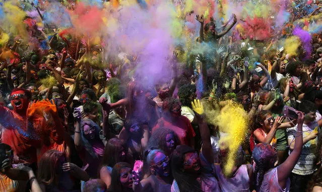 Visitors of the Holi Festival of Colors throw colored powders in the air in Santa Coloma de Gramenet, Spain, Sunday, May 28, 2017. The festival is fashioned after the Hindu spring festival Holi, which is mainly celebrated in the north and east of India. (Photo by Manu Fernandez/AP Photo)