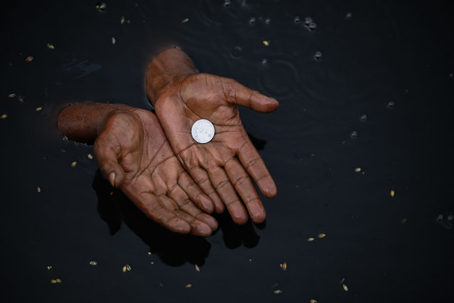 A man takes a dip in the waters of river Yamuna looking for coins and other reusable items usually immersed in the river by people observing various religious beliefs in New Delhi on April 23, 2022. (Photo by Sajjad Hussain/AFP Photo)