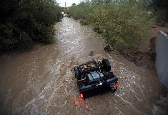Water rushes around a vehicle near S. Elizabeth Drive and W. Lincoln Street after a storm, Tuesday, July 28, 2015, in Tucson, Ariz. The occupants of the vehicle made it out safely. Photo by (Mamta Popat/Arizona Daily Star via AP Photo)