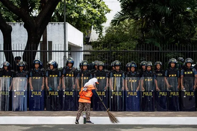 A cleaner sweeps in front of police standing in formation near the venue of the Association of Southeast Asian Nations (ASEAN) summit off Manila Bay on April 26, 2017. Firebrand Philippine President Rodrigo Duterte is set to enjoy much-wanted foreign support for his deadly drug war when he hosts Southeast Asian leaders at the Manila summit this week, observers say. (Photo by Noel Celis/AFP Photo)