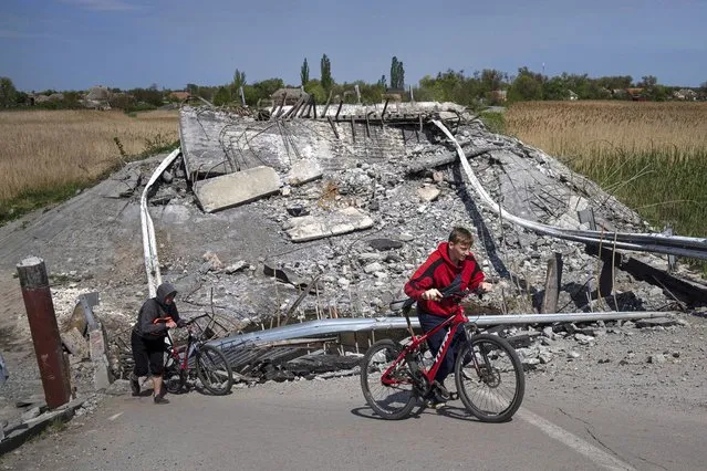 Teenagers on bicycles pass a bridge destroyed by shelling near Orihiv, Ukraine, Thursday, May 5, 2022. (Photo by Evgeniy Maloletka/AP Photo)