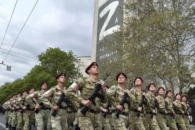 Russian National Guard (Rosguardia) servicemen march through a street with a letter Z, which has become a symbol of the Russian military on a building in Sevastopol, Crimea, Thursday, May 5, 2022. (Photo by AP Photo/Stringer)