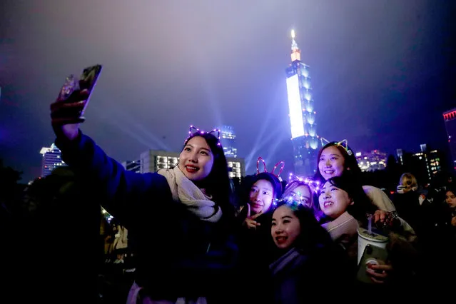 People take a photo after the Fireworks and light effects display from the Taipei 101 skyscraper during New Year's Eve celebrati​ons in Taipei, Taiwan, 01 January 2020. (Photo by Ritchie B. Tongo/EPA/EFE)