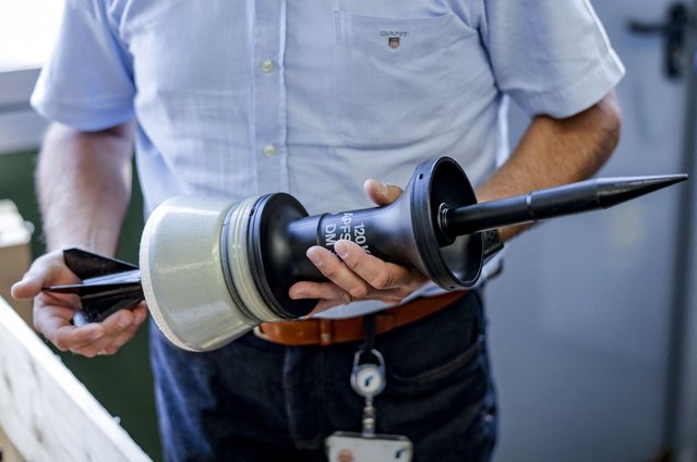 An employee of German armaments company and automotive supplier Rheinmetall shows a projectile of 120mm ammunition for Leopard battle tanks that will be delivered to Ukrainian Forces, at the facility of Rheinmetall in Unterluess, northern Germany, on June 6, 2023. Since Russia invaded Ukraine, Germany has dropped a traditionally pacifist stance and become one of Ukraine's biggest military backers, delivering a wide array of weaponry to Kyiv. Rheinmetall has received a boost from the Ukraine war, posting record results in 2022 and joining Frankfurt's blue-chip DAX index in March 2023. (Photo by Axel Heimken/AFP Photo)