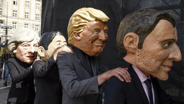 Demonstrators  against the G20 Summit stand on stage wearing masks depicting  from left : British Prime Minister Theresa May, Japan's Prime Minister Shinzo Abe, US President Donald Trump and French President Emmanuel Macron, in Hamburg, Germany, Sunday, July 2, 2017. (Photo by Axel Heimken/DPA via AP Photo)