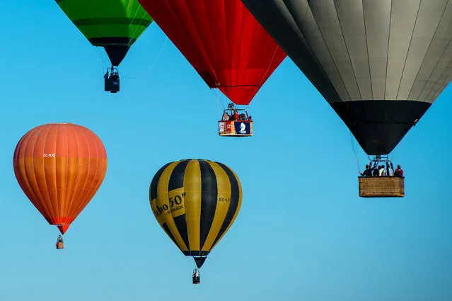 Hot air balloons fly over Igualada during an early flight as part of the European Balloon Festival on July 10, 2014 in Igualada, Spain. The early morning flight of over 30 balloons was shorter than expected due to windy weather. This flight is organised as a curtain raiser for the four-day European Balloon Festival. Now is the 18th year of the most important hot air Balloon event in Spain and one of the biggest in Europe. (Photo by David Ramos/Getty Images)