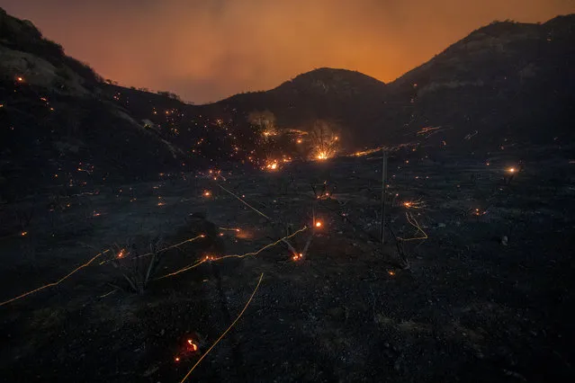 A time exposure shows embers from Saddleridge Fire blown by the wind in the Porter Ranch section of Los Angeles, California, on October 11, 2019. The fire broke out late October 10 and has scorched some 4,600 acres (1,816 hectares), and forced mandatory evacuation orders for 12,700 homes. (Photo by David McNew/AFP Photo)