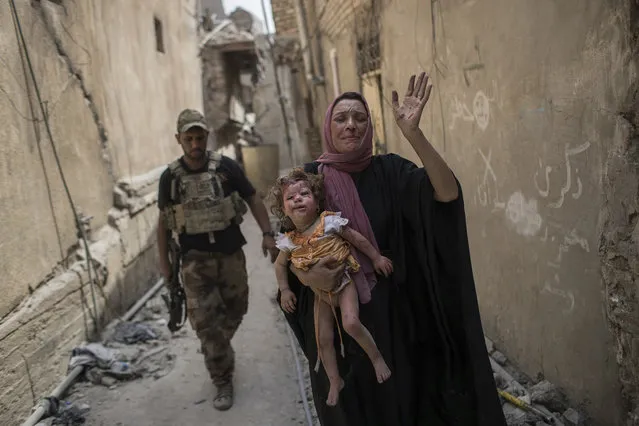 A woman holds a young injured girl as Iraqi forces continue their advance against Islamic State militants in the Old City of Mosul, Iraq, Monday, July 3, 2017. (Photo by Felipe Dana/AP Photo)