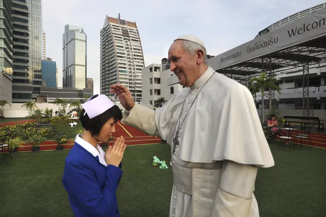 A nurse bows to the life size statue of Pope Francis as her friend takes a photograph at the St.Louis hospital in Bangkok, Thailand, Tuesday, November 19, 2019. Pope Francis arrives in Thailand on Wednesday for the first visit here by the head of the Roman Catholic Church since St. John Paul II in 1984. (Photo by Manish Swarup/AP Photo)