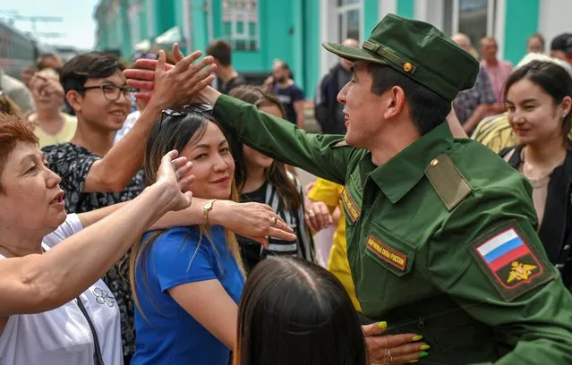 A conscript, wearing a military uniform, farewells with family members at a local railway station during departure for the garrisons, in Omsk, Russia on June 17, 2022. (Photo by Alexey Malgavko/Reuters)