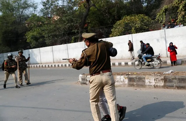 A police officer detains an unidentified man after he brandished a gun and injured a student during a protest against a new citizenship law outside the Jamia Millia Islamia university in New Delhi, India, January 30, 2020. “He was in front of all the people – protesters and policemen who were standing nearby, but he jumped in from this side, brandished the gun and said 'Come I will give you freedom',” a witness who gave his name as Aamir said. (Photo by Danish Siddiqui/Reuters)