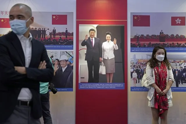 Visitors stand in front of a photo showing Chinese president Xi Jinping and his wife Peng Liyuan in Hong Kong at an exhibition to celebrate the 25th anniversary of Hong Kong handover to China in Hong Kong, Friday, June 24, 2022. (Photo by Kin Cheung/AP Photo)