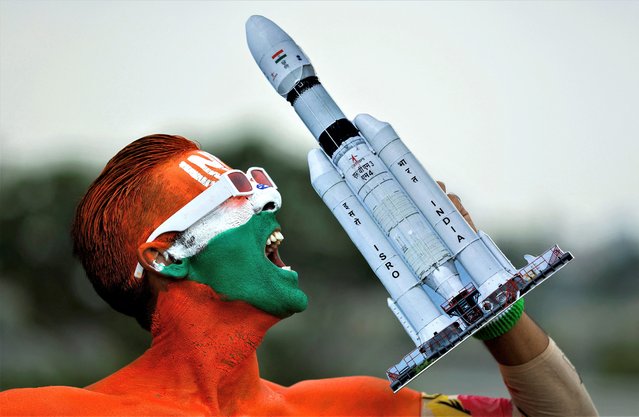 Arun Haryani, an enthusiast with his body painted in tri-colours reacts as he holds up a model of LVM3 M4 which was used in launching of Chandrayaan-3 spacecraft on the eve of its moon landing, in Ahmedabad, India on August 22, 2023. (Photo by Amit Dave/Reuters)