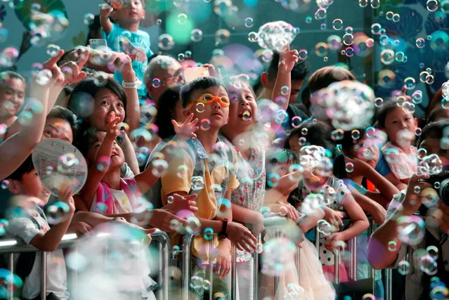 People react in front of bubbles, during a “Bubble Up” show by Japanese artist Shinji Ohmaki, outside Harbour City mall in Hong Kong, China August 4, 2017. (Photo by Bobby Yip/Reuters)