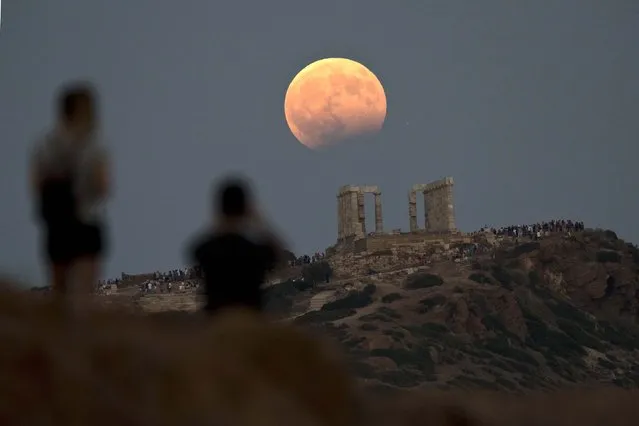 The August full moon rises above the 5th Century BC Temple of Poseidon at Cape Sounio, south of Athens, on Monday, August 7, 2017. More than a hundred of Greece's ancient sites – but not the Acropolis in Athens – and museums were kept open until late Monday and concerts organized to allow visitors to enjoy the full moon, which is accompanied by a partial lunar eclipse. (Photo by Petros Giannakouris/AP Photo)