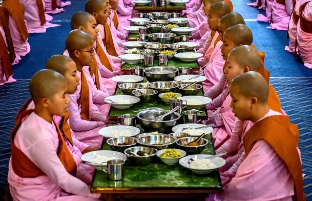 This photograph taken on January 15, 2020 shows Buddhist novice nuns praying before breakfast at a monastic school in Sagaing outside Mandalay. In keeping with Buddhist traditions, both nuns and monks refrain from eating from midday until breakfast the following morning. Myanmar is a Buddhist-majority country. (Photo by Mladen Antonov/AFP Photo)