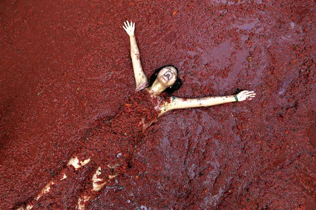 A woman reacts during the annual tomato fight fiesta called “Tomatina” in the village of Bunol near Valencia, Spain, Wednesday, August 30, 2023. Thousands gather in this eastern Spanish town for the annual street tomato battle that leaves the streets and participants drenched in red pulp from 120,000 kilos of tomatoes. (Photo by Alberto Saiz/AP Photo)