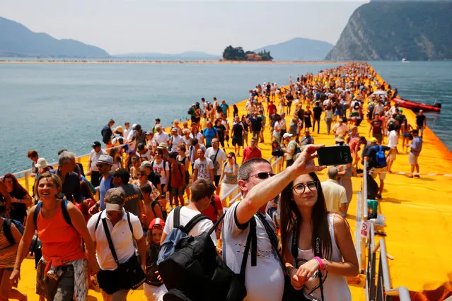 People take selfies on the installation “The Floating Piers” on Lake Iseo by Bulgarian-born artist Christo Vladimirov Yavachev, known as Christo, at the installation's last weekend near Sulzano, northern Italy, July 2, 2016. (Photo by Wolfgang Rattay/Reuters)