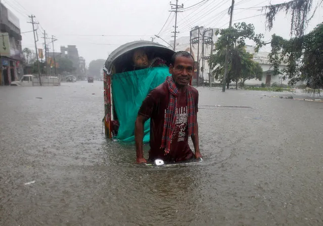 A man pedals a rickshaw as he helps a passenger wade through a waterlogged street during heavy rains in Agartala, India August 11, 2017. (Photo by Jayanta Dey/Reuters)