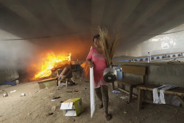 An Indonesian woman carries away household goods from a fire at an illegal housing complex under a highway bridge on August 19, 2015 in Jakarta, Indonesia. A fire broke out as nearly one hundred residents of the makeshift compound many who had been living there for nearly 10 years were evicted as Jakarta's government tries to clear non-official housing from public areas despite the shortage of low cost housing for the poor.  (Photo by Ed Wray/Getty Images)
