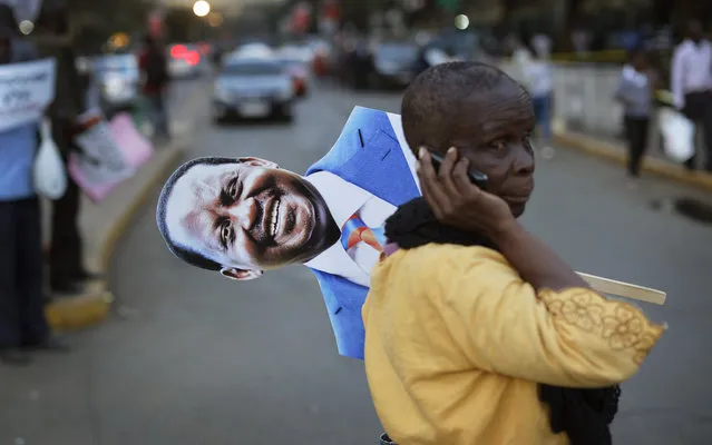 A supporter of main opposition leader Raila Odinga holds a placard of his face as she attends a small demonstration outside the Supreme Court in downtown Nairobi, Kenya Friday, August 18, 2017. Dozens of supporters gathered in front of the court building where opposition lawyers were expected to file a petition contesting President Uhuru Kenyatta's re-election. (Photo by Ben Curtis/AP Photo)