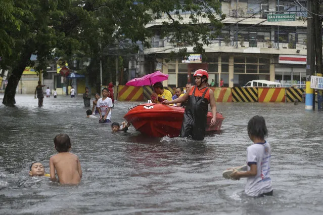 Filipino rescuers ferry residents on a rubber boat along a flooded road in suburban Mandaluyong, east of Manila, Philippines, as monsoon downpours intensify while Typhoon Nepartak exits the country on Friday, July 8, 2016. In the Philippine capital, Manila, and outlying provinces, classes in many schools were suspended and at least six flights, including one scheduled to come from Taiwan, were canceled because of stormy weather and floods following monsoon downpours intensified by the typhoon, Filipino officials said. (Photo by Aaron Favila/AP Photo)