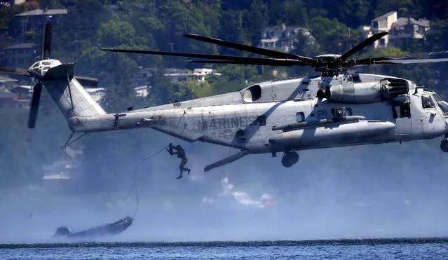 A U.S. Marine jumps from a helicopter after a raft is dropped as part of a demonstration during the Seafair Air Show, Sunday, August 3, 2014, in Seattle. (Photo by Ted S. Warren/AP Photo)