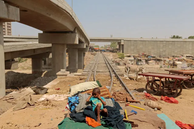 A child from a homeless family sits on a bed, on the track of the disused Karachi Circular Railway line in Karachi, Pakistan, May 23, 2017. After many false starts, plans to resurrect a railway in Pakistan's teeming metropolis of Karachi are moving ahead with the help of Chinese cash. Not everyone is happy. The Chinese-funded project to revive Karachi Circular Railways (KRC), nearly two decades since it was shut down, has been touted as a way to ease pollution and chronic congestion in the port city. It is also viewed with suspicion by Pakistanis who have built homes and businesses along the route connecting Karachi's sprawling suburbs with the industrial and commercial areas of the megacity. (Photo by Caren Firouz/Reuters)