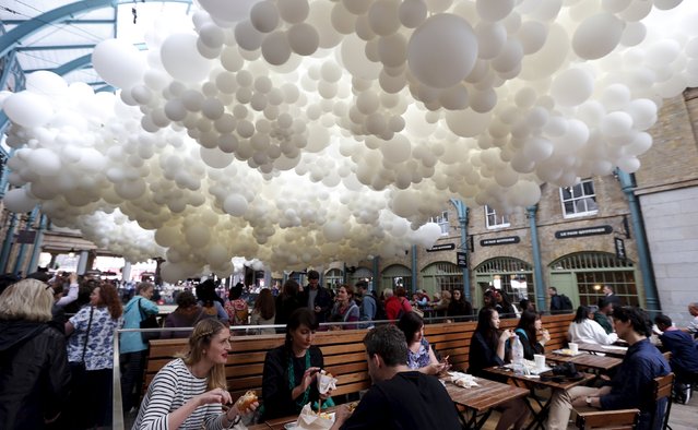 People eat lunch under an art installation made of over 100,000 white balloons by French artist Charles Petillon in Covent Garden market in London, Britain, August 27, 2015. (Photo by Suzanne Plunkett/Reuters)