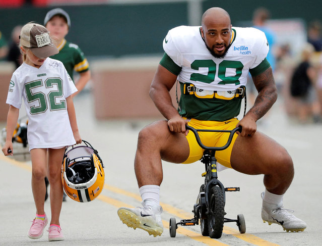 A young fan watches as Green Bay Packers running back AJ Dillon (28) tries his best to ride her bicycle to training camp on Monday, August 1, 2022, at Ray Nitschke Field in Green Bay, Wis. (Photo by Dan Powers/USA TODAY Sports)