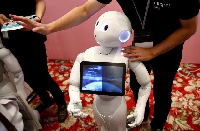 A man touches SoftBank humanoid robot known as Pepper as he demonstrates its translation function at Pepper World 2016 Summer during SoftBank World 2016 conference in Tokyo, Japan, July 21, 2016. (Photo by Kim Kyung-Hoon/Reuters)