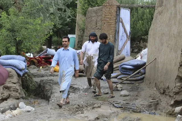 People walk among their damaged homes after heavy flooding in the Khushi district of Logar province south of Kabul, Afghanistan, Sunday, August 21, 2022. (Photo by Shafiullah Zwak/AP Photo)