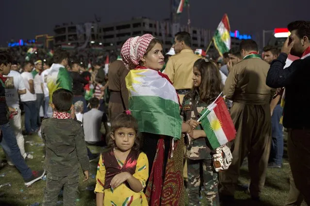 A woman stands with her children on the crowd at a referendum rally in Irbil, Friday, September 22, 2017. Thousands gathered in the Irbil soccer stadium in support of Monday's referendum vote for Kurdish independence. (Photo by Bram Janssen/AP Photo)