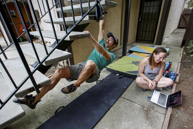 Scott Fong practices rock climbing on a staircase outside his home as his partner Claire Brady video chats with her family in place of their annual gathering on Good Friday, as 40 million Californians continue to shelter in place due to the coronavirus disease (COVID-19) outbreak, in Redwood City, California, U.S. April 10, 2020. (Photo by Stephen Lam/Reuters)