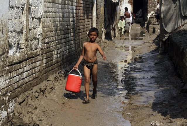 An affected boy walks along a muddy street after heavy rain in Nowshera district of Khyber Pakhtunkhwa, Pakistan, Friday, September 2, 2022. Planes carrying fresh supplies are surging across a humanitarian air bridge to flood-ravaged Pakistan as the death toll surged past 1,200, officials said Friday, with families and children at special risk of disease and homelessness. (Photo by Mohammad Sajjad/AP Photo)