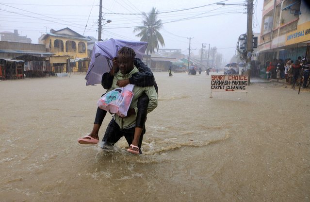 A man wades through flood waters along a street following heavy rains in Kisauni district of Mombasa, Kenya on November 17, 2023. (Photo by Reuters/Stringer)