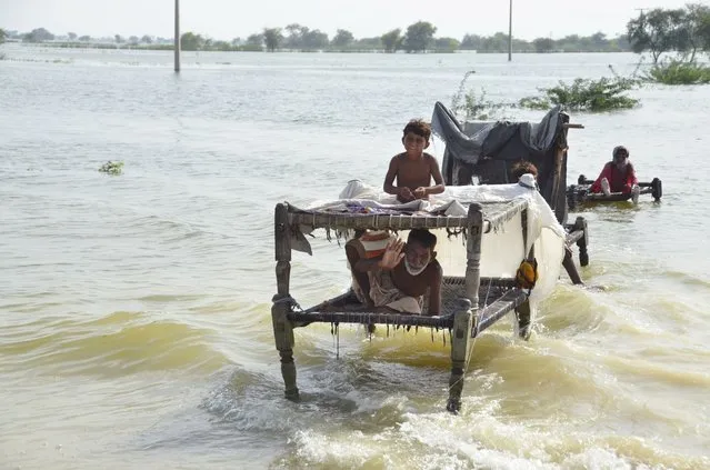 A man sits near his belongings surrounded by floodwaters, in Sohbat Pur city, a district of Pakistan's southwestern Baluchistan province, Saturday, September 3, 2022. The homeless people affected by monsoon rains triggered devastating floods in Pakistan get enhancing international attention amid growing numbers of fatalities and homeless families across the country as the federal planning minister appealed the international community for immense humanitarian response for 33 million people. (Photo by Zahid Hussain/AP Photo)