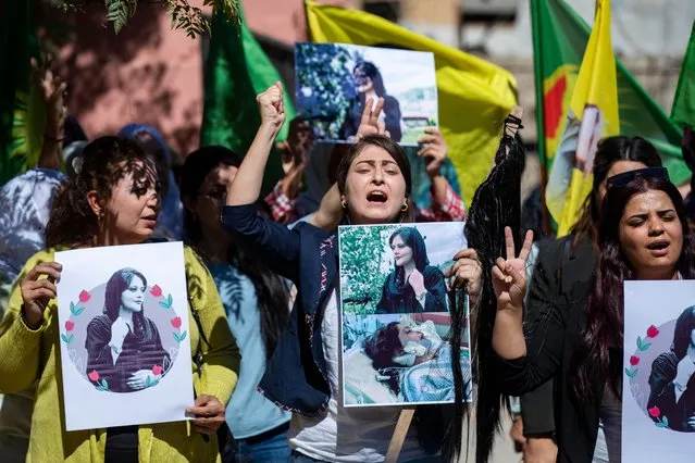 Syrian Kurdish women take part in a demonstration in Syria's northeastern city of Hasakeh on September 25, 2022, to express their support for 22-year-old Mahsa Amini (portrait), who died while in the custody of Iranian authorities. Amini, whose Kurdish first name is Jhina, was arrested on September 13 for allegedly breaching the rules that mandate tightly-fitted hijab head coverings and which ban, among other things, tight trousers and brightly coloured clothes. (Photo by Delil Souleiman/AFP Photo)