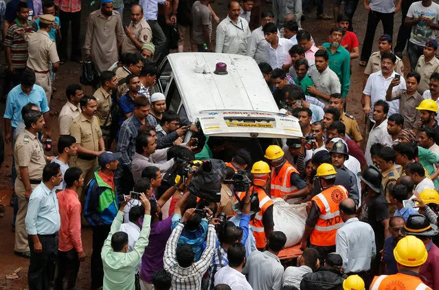 Rescue workers carry the body of a victim after recovering it from the debris at the site of a collapsed residential building on the outskirts of Mumbai, India, August 7, 2016. (Photo by Shailesh Andrade/Reuters)