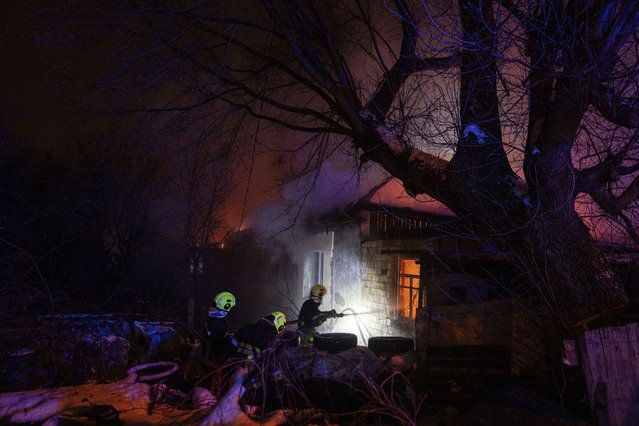 Rescue workers extinguish a fire at a residential house after a Russian rocket attack in Kyiv, Ukraine, Wednesday, December 13, 2023. (Photo by Evgeniy Maloletka/AP Photo)