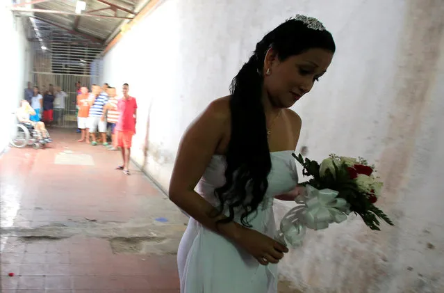 A woman in a wedding gown walks to a mass wedding ceremony, held 17 male inmates, in the Carcel Villa Hermosa prison in Cali, Colombia, August 19, 2016. (Photo by Jaime Saldarriaga/Reuters)