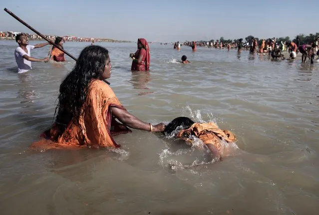 Dholak Kumari (L), an assistant shaman of Paltan Mukhiya (unseen), grabs the hair of Rinku Yadav (R), aged 20, for a holy dip during the Ghost Festival at the banks of Kamala River in Dhanusha district, Nepal, 04 November 2017. Rinku is mother of a two-year-old girl. Her husband has migrated to Kuwait for a labor job one year ago. (Photo by Narendra Shrestha/EPA/EFE)