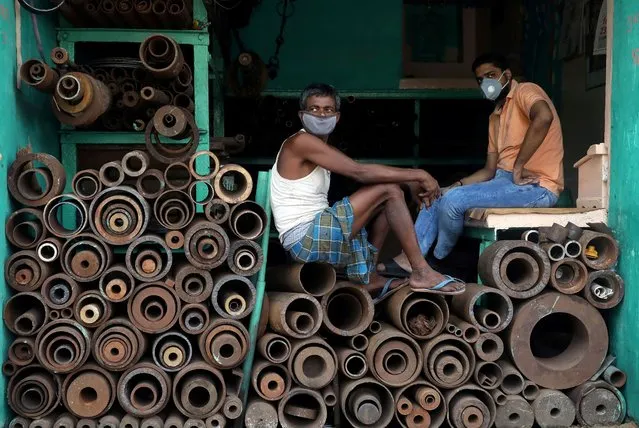 Workers wearing protective face masks sit inside a shop selling iron pipes at a wholesale iron market, after authorities eased lockdown restrictions that were imposed to slow the spread of the coronavirus disease (COVID-19), in Kolkata, India, June 15, 2020. (Photo by Rupak De Chowdhuri/Reuters)