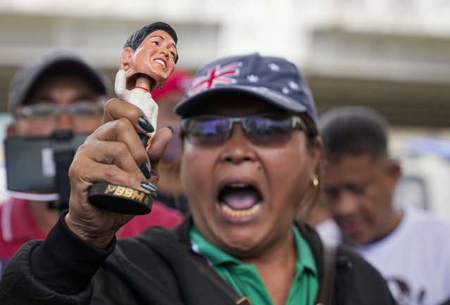 A supporter of former Philippine President Rodrigo Duterte shouts slogans holding a doll bearing the face of Philippine President Ferdinand Marcos Jr. as they hold a rally outside Villamor airbase after Duterte was arrested, Tuesday, March 11, 2025, near Manila, Philippines. (Photo by Aaron Favila/AP Photo)