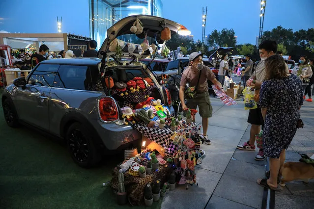 This photo taken on June 21, 2020 shows a man (L) using the trunk of his car to sell items in Shenyang, in China's northeastern Liaoning province. (Photo by AFP Photo/China Stringer Network)