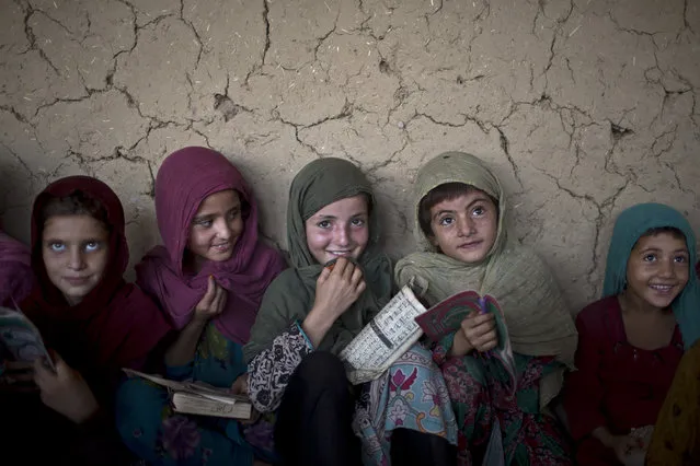 In this Monday, August 11, 2014, photo, Afghan refugee girls listen to their teacher during their daily Madrassa, or Islamic school, at a mosque on the outskirts of Islamabad, Pakistan. (Photo by Muhammed Muheisen/AP Photo)