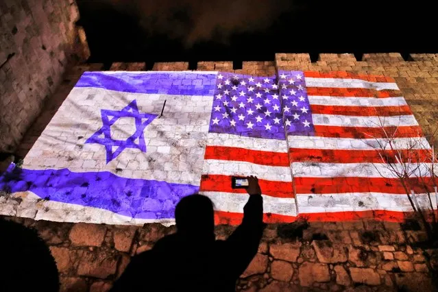 A picture taken on December 6, 2017 shows a giant US flag screened alongside Israel's national flag by the Jerusalem municipality on the walls of the old city. US President Donald Trump recognized the disputed city of Jerusalem as Israel's capital on December 6, 2017, and kicked off the process of relocating the US embassy there from Tel Aviv. The old city lies in the eastern part of Jerusalem which was under Jordanian control from Israel's creation in 1948 until Israeli forces captured it during the 1967 Six-Day War, and Israel later annexed it in a move not recognised by the international community. (Photo by Ahmad Gharabli/AFP Photo)