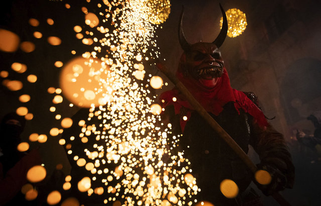 A participant dressed up as a demon brandishes a stick with fireworks among revellers during the traditional Correfoc (fire-run) festival in Palma de Mallorca on January 28, 2024. The Correfoc is a night of revelry in which participants dress up as demons and devils, and run through the streets scaring people with fire and fireworks. (Photo by Jaime Reina/AFP Photo)