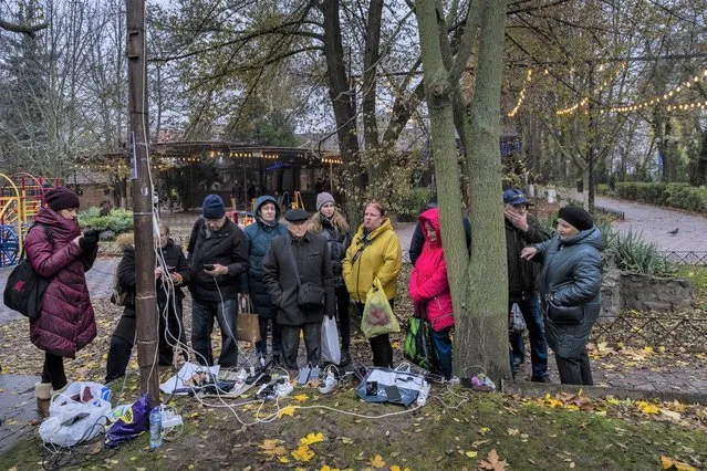 Residents plug in mobile phones and power banks at a charging point in downtown Kherson, southern Ukraine, Sunday, November 20, 2022. Russian forces fired tank shells, rockets and other artillery on the city of Kherson, which was recently liberated from Ukrainian forces. (Photo by Bernat Armangue/AP Photo)
